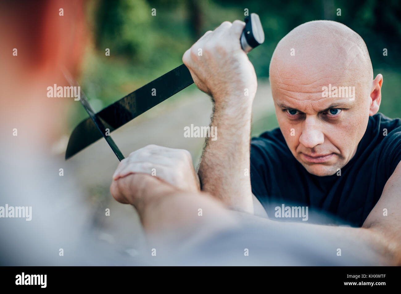 Martial arts instructor demonstrates machete fighting concept. Long