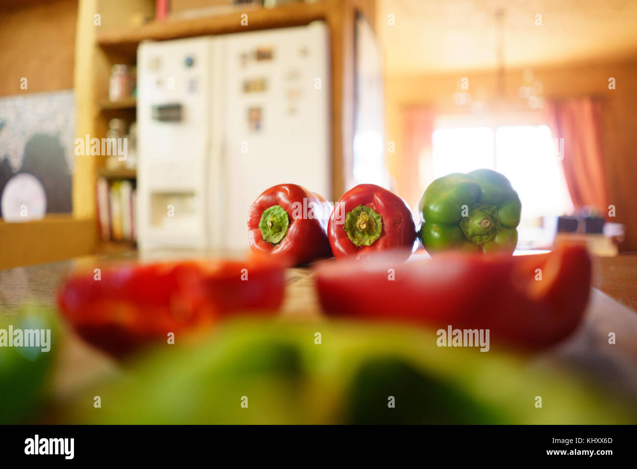 Whole and half red and green peppers on kitchen counter Stock Photo