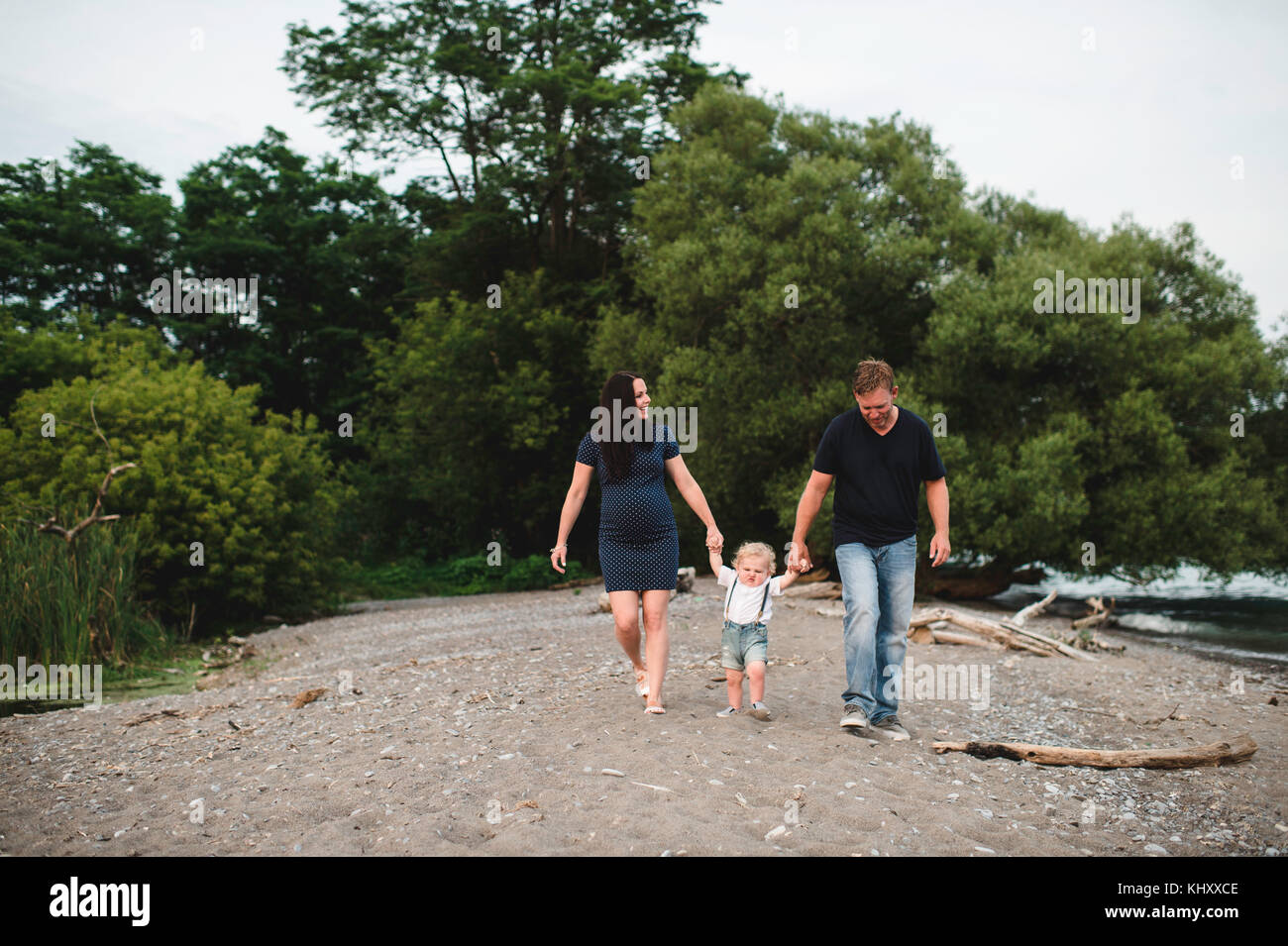 Pregnant couple strolling on beach with male toddler son, Lake Ontario, Canada Stock Photo