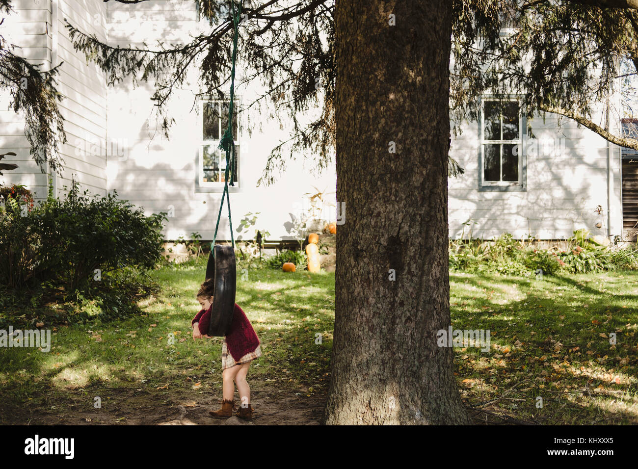 Girl on tyre swing hanging from tree Stock Photo