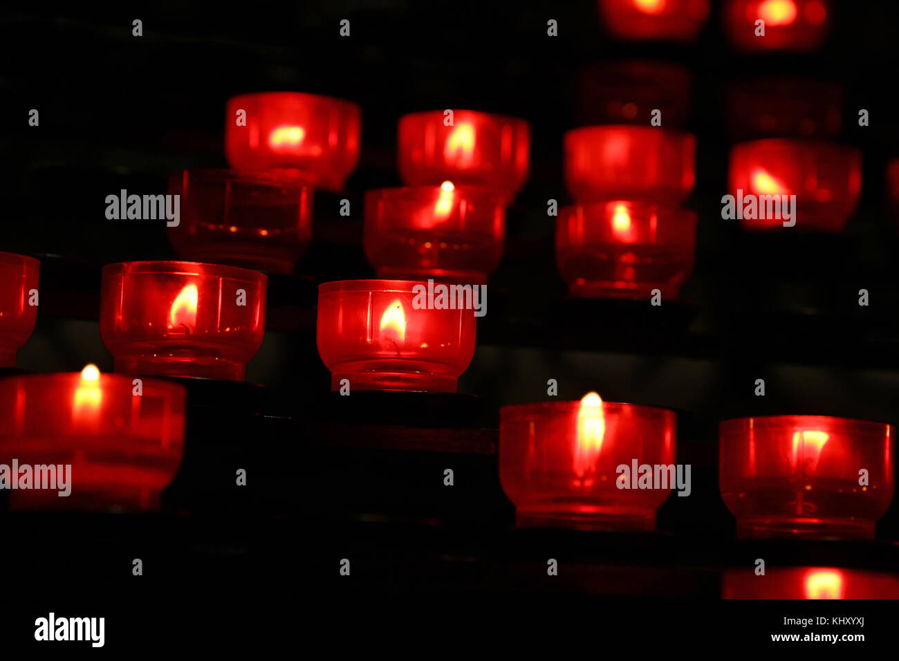 Red translucent candles burning in dark church, close up, low angle ...