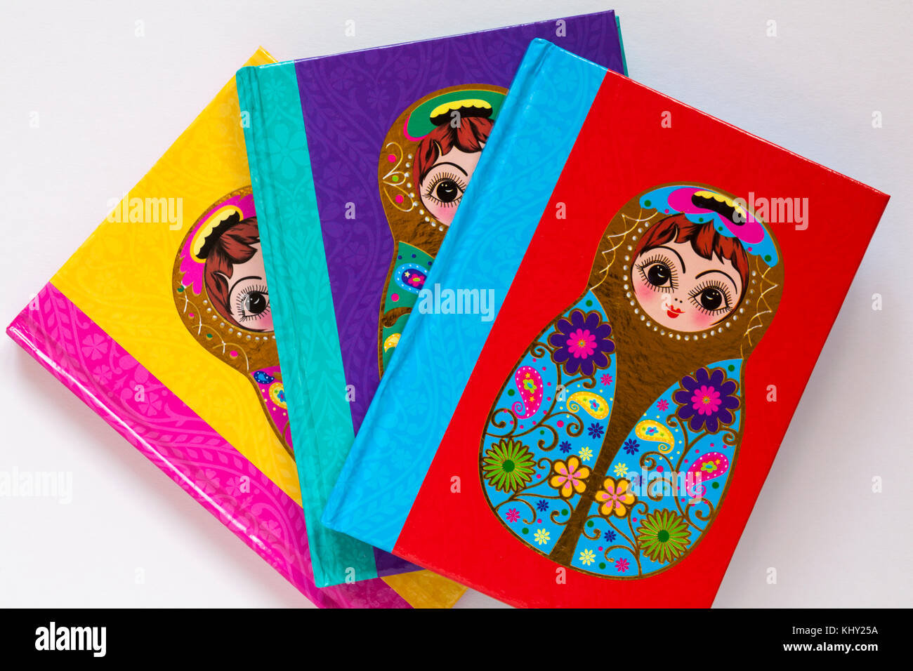 Three different coloured note books with matryoshka doll on cover set on white background Stock Photo