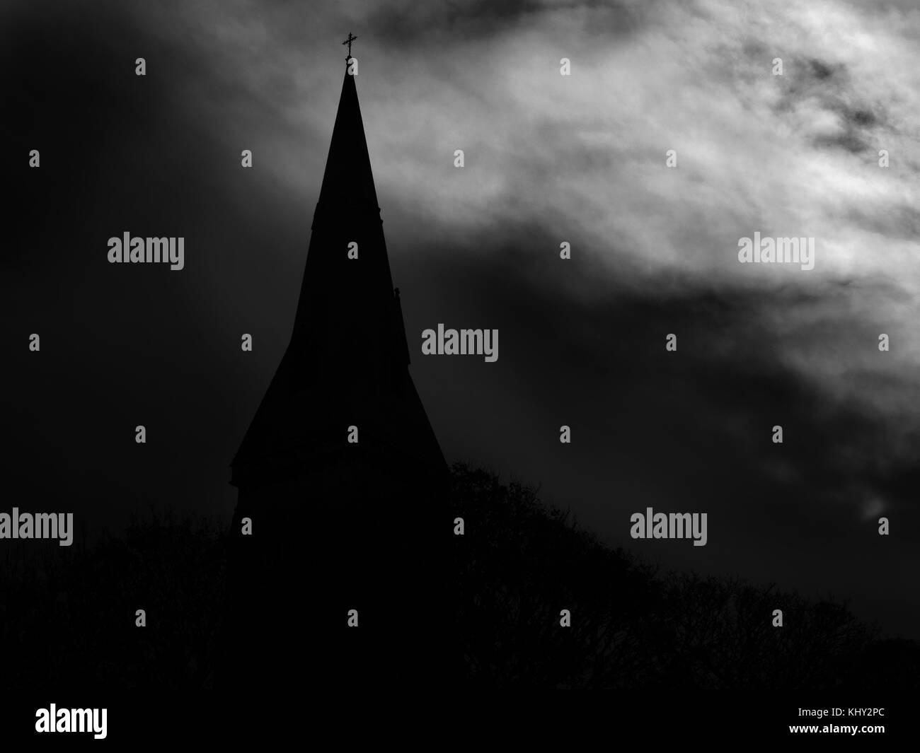Silhouette of Holy Trinity Church Spire against a Dark Cloudy Sky Knaresborough North Yorkshire England Stock Photo