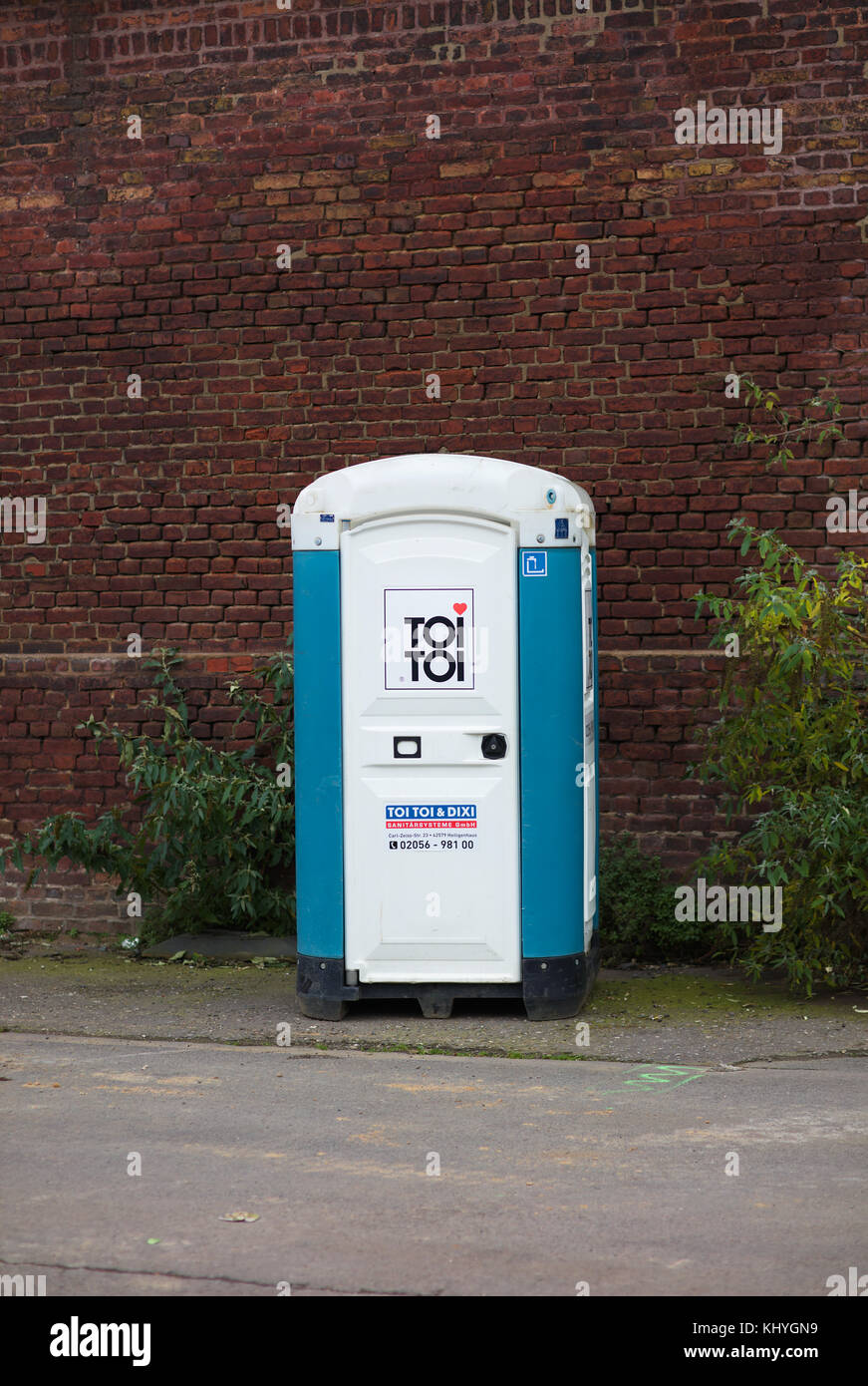 Mobile toilet in front of a brick wall Stock Photo