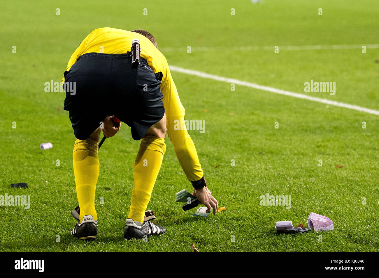 A goal line referee collects play money that was thrown on the pitch by FC Bayern Munich fans during the Champions League soccer match between RSC Anderlecht and Bayern Munich in Anderlecht, Belgium, 22 November 2017. Photo: Marius Becker/dpa Stock Photo
