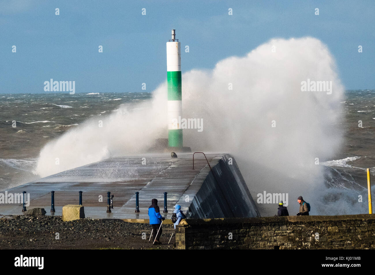 Aberystwyth Wales UK, Thursday 23 November 2017 UK Weather: A group of walkers look on as high tides and very strong winds combine to bring waves crashing into the sea defences and the harbour lighthouse in Aberystwyth, on the Cardigan Bay coast of west wales. photo Credit: Keith Morris/Alamy Live News Stock Photo