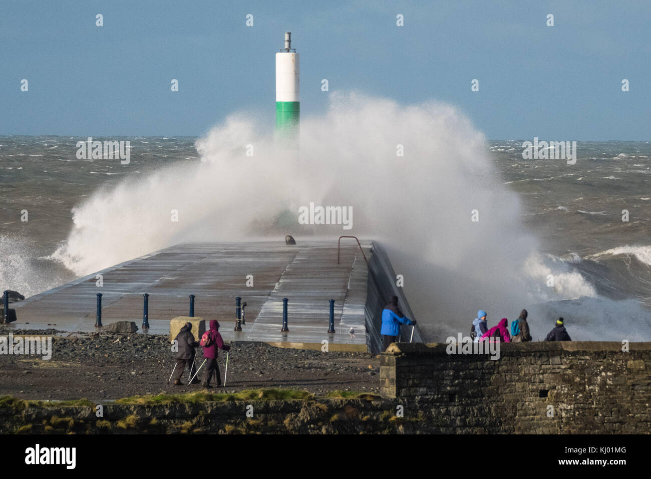 Aberystwyth Wales UK, Thursday 23 November 2017 UK Weather: A group of walkers look on as high tides and very strong winds combine to bring waves crashing into the sea defences and the harbour lighthouse in Aberystwyth, on the Cardigan Bay coast of west wales. photo Credit: Keith Morris/Alamy Live News Stock Photo