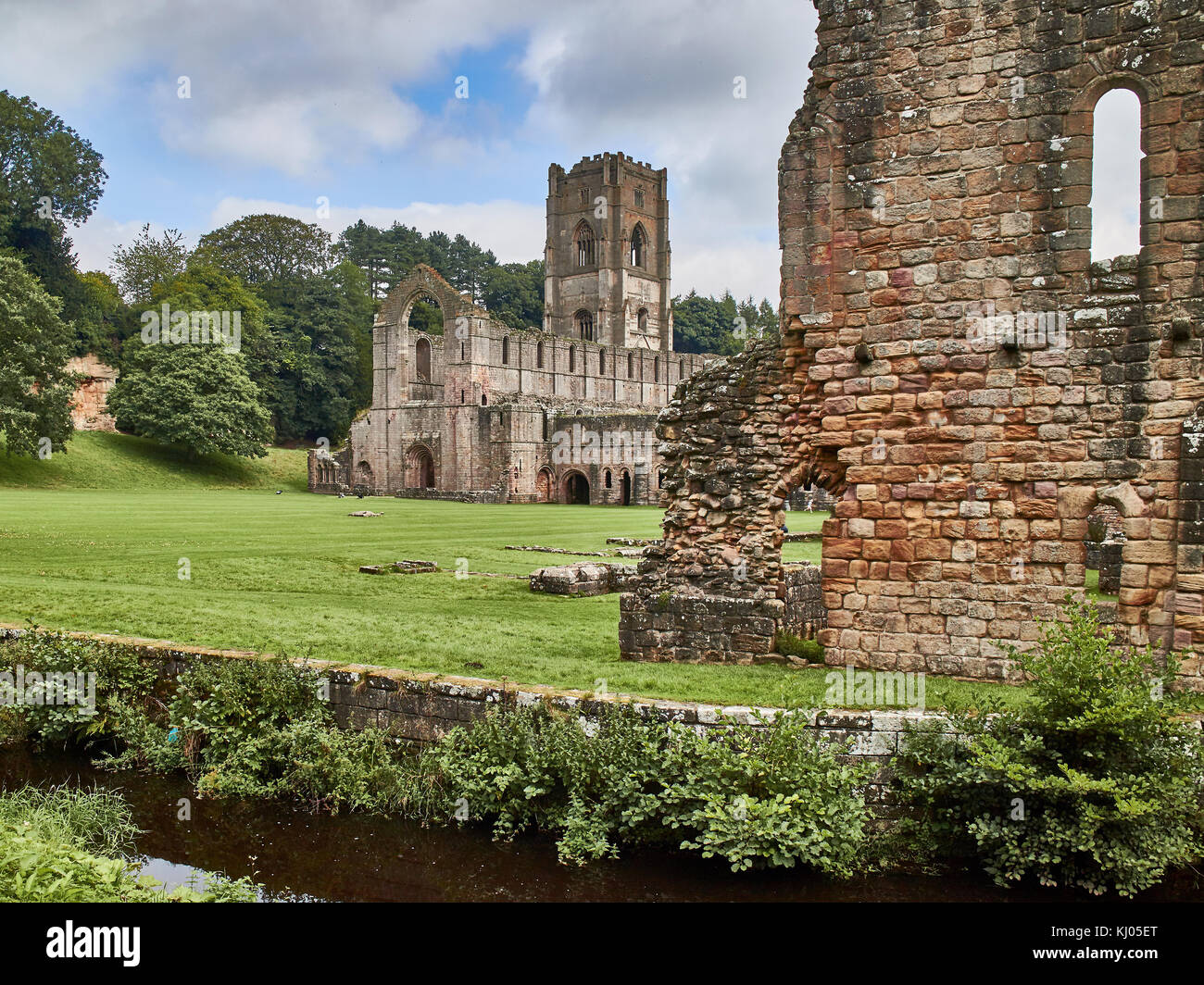 England, NorthYorkshire; the ruins of the 12th century Cistercian Abbey known as Fountains Abbey, one of the finest examples of monastic architecture in the world. The tower by Abbot Huby, (1495-1526), still dominates the valley landscape. Together with its surrounding 800 acres of 18th century landscaped parkland, Fountains Abbey has been designated a UNESCO World Heritage Site. North Yorkshire, England, UK. Ca. 1995. | Location: near Ripon, Yorkshire, England, UK. Stock Photo