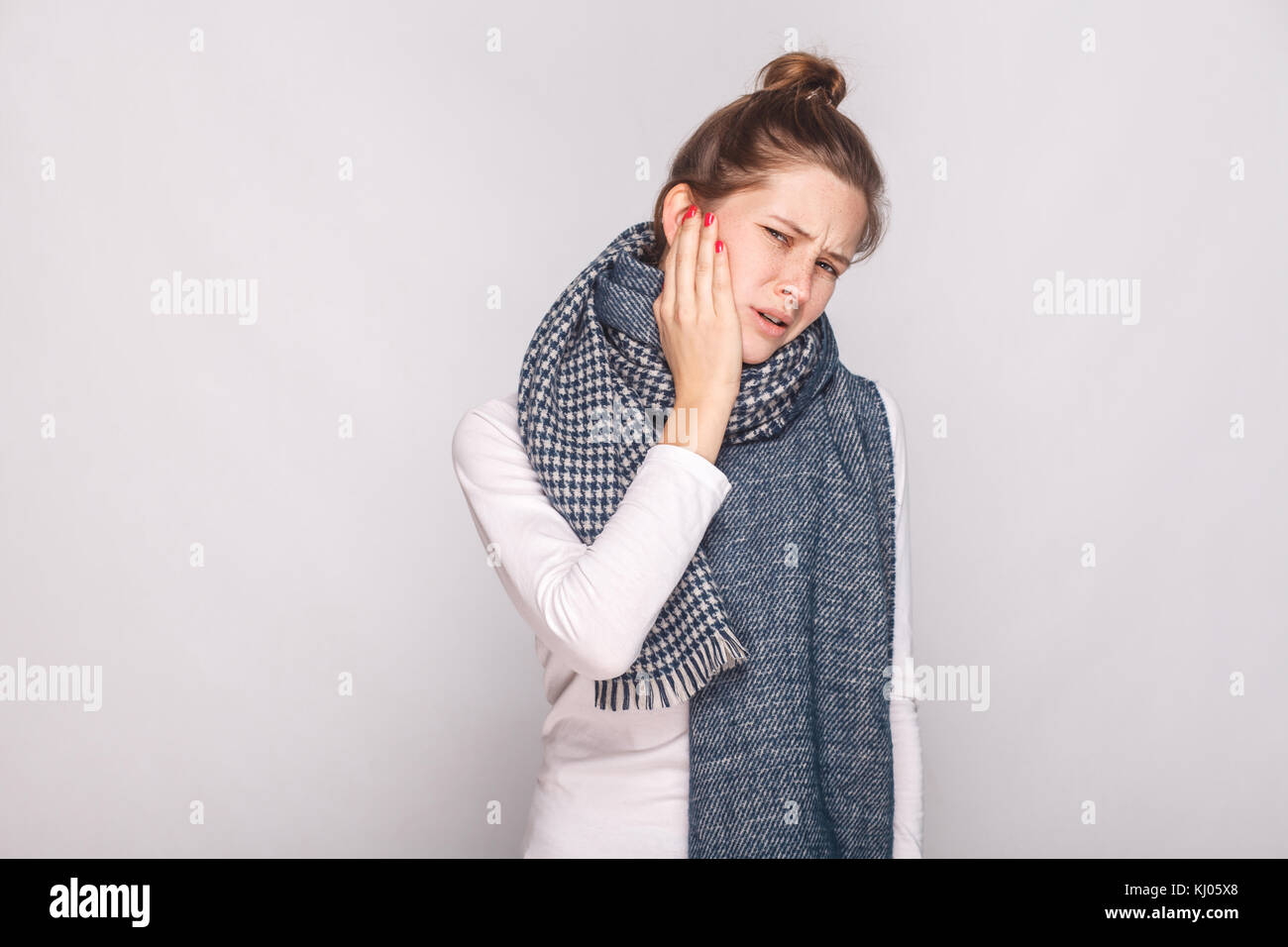 Sick woman holding hand her cheeh, have a toothache. Studio shot, gray wall Stock Photo