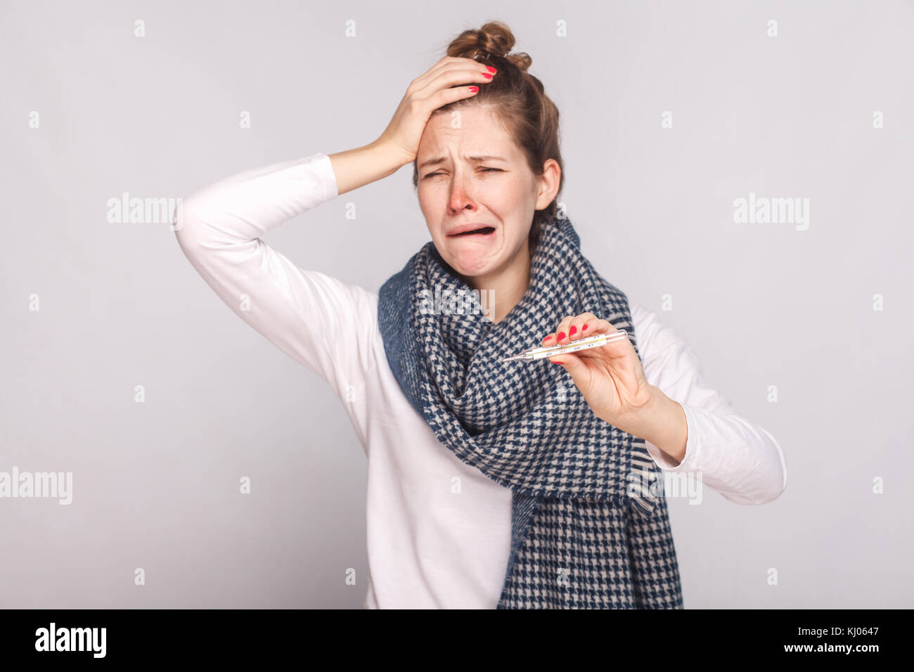 Unwell sick woman have temperature, holding head and cry. Studio shot, isolated on gray background Stock Photo