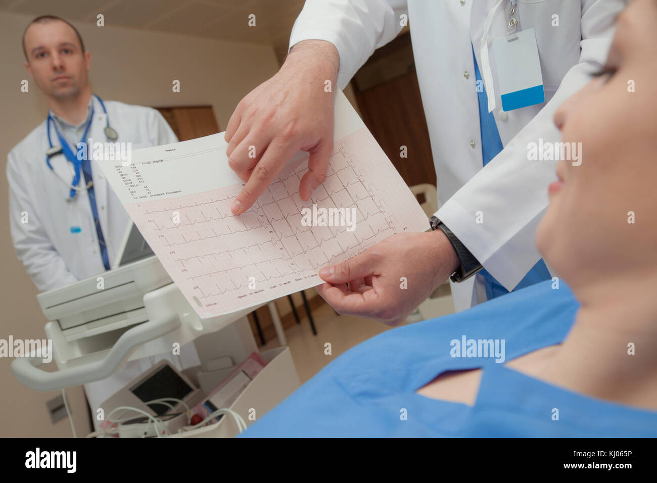 A cardiogram with a normal heart beat rate is shown to a pleased young female patient. Stock Photo