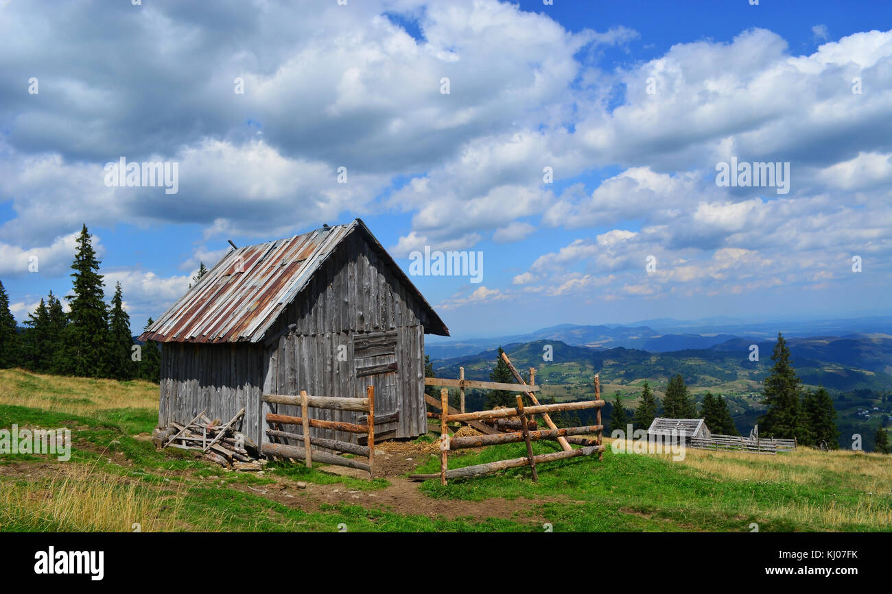 Small cabin located on the top of the hill with the view of the mountains and forest. Stock Photo
