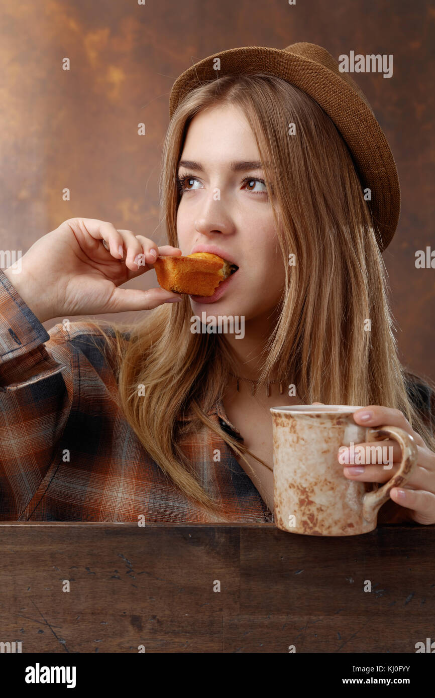 Young beautiful blonde in a brown plaid shirt with a mug of coffee and