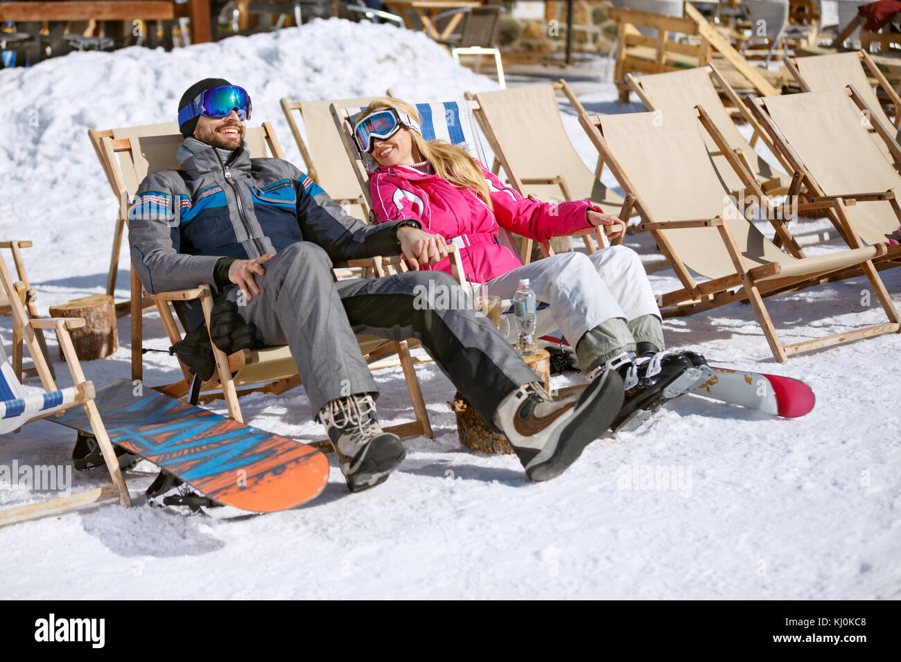 Male and female skiers enjoy in sun loungers on ski terrain Stock Photo