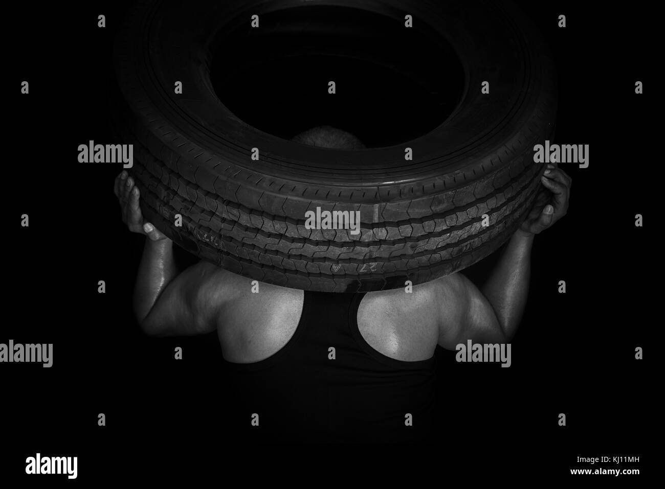 Strong worker holds big truck tire Stock Photo