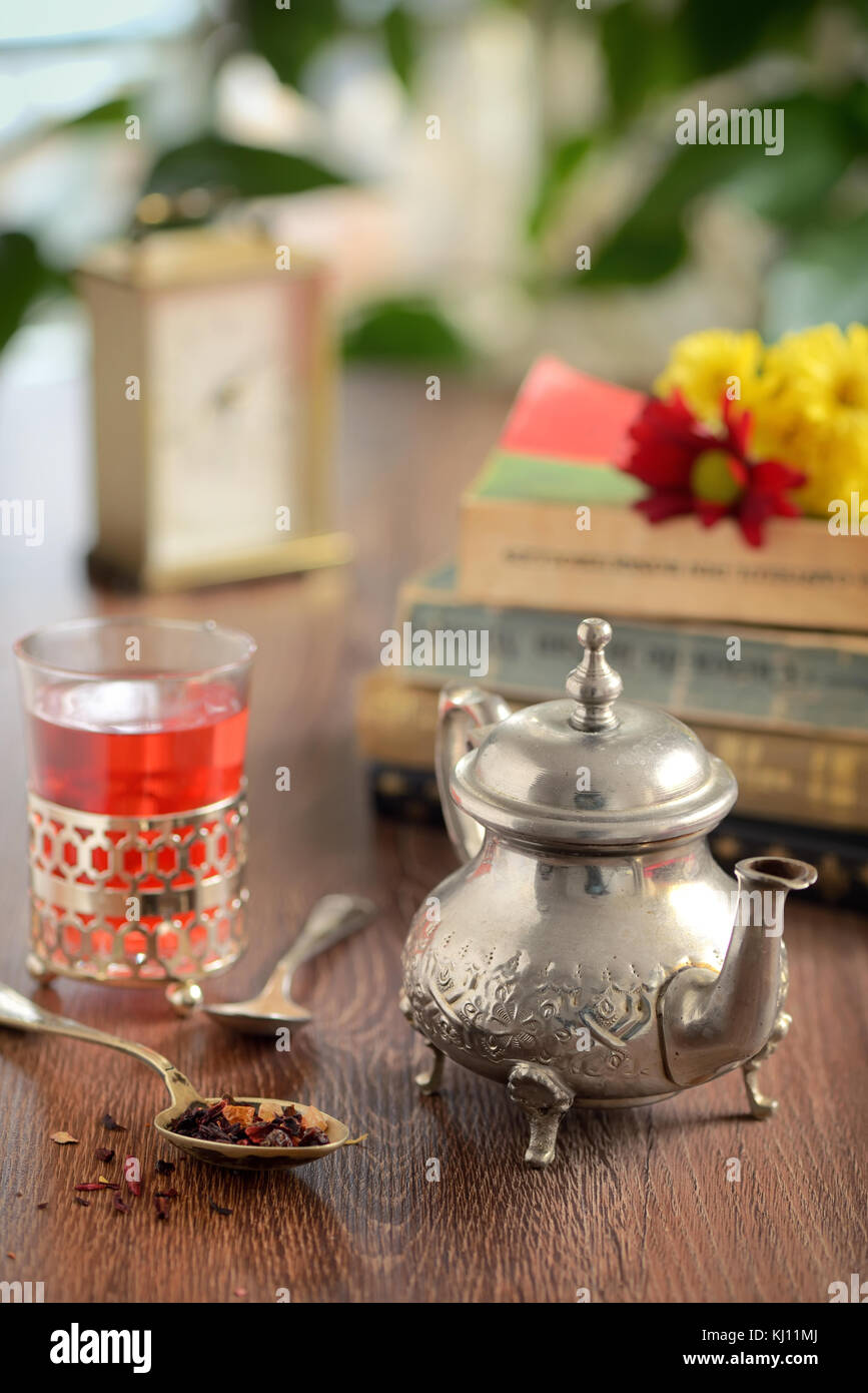 Dry tea leaves on spoon and teapot on wooden table Stock Photo