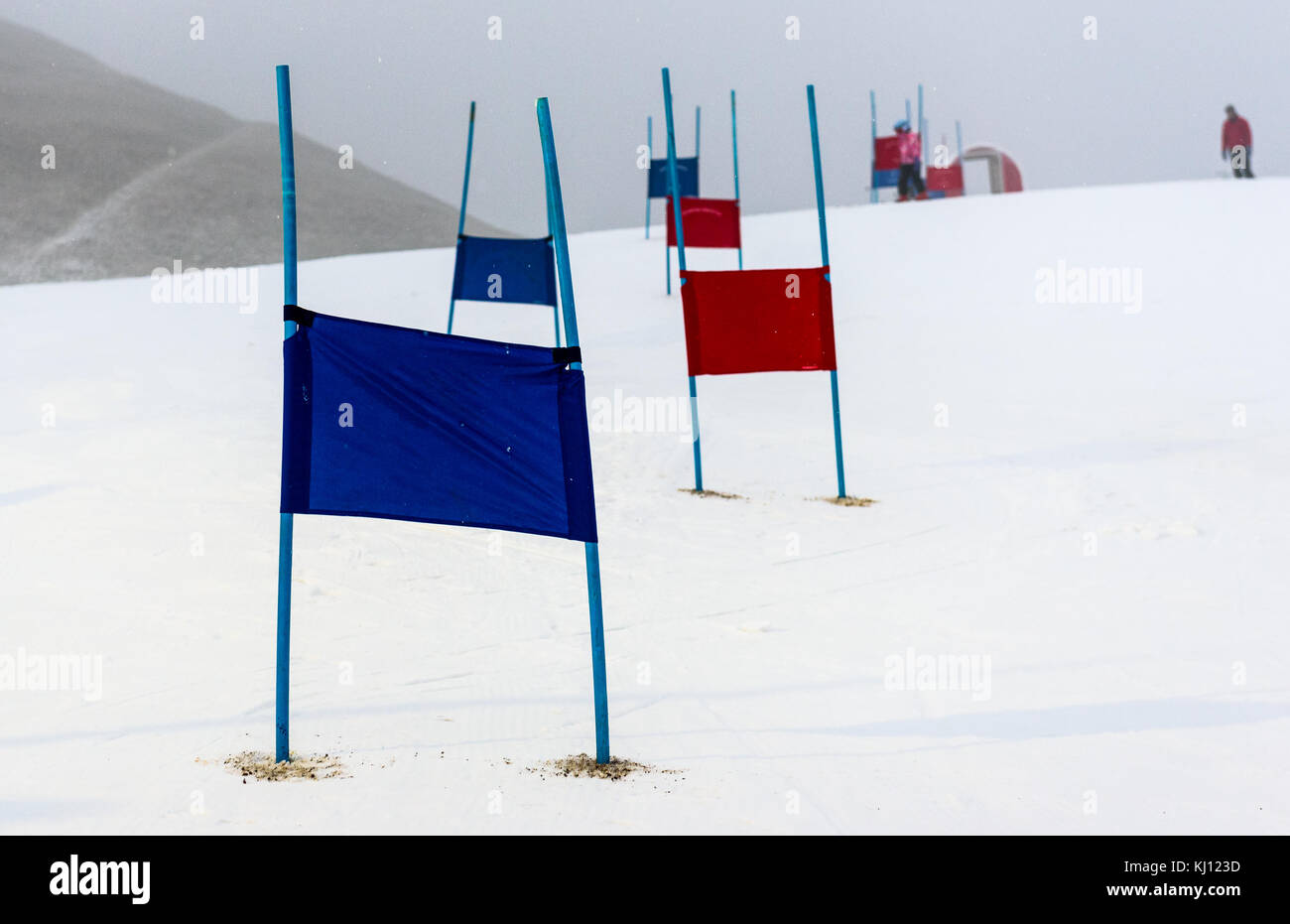 Children skiing slalom racing track with blue and red gates. Small ski race gates on a pole with children skiing in the background. Stock Photo