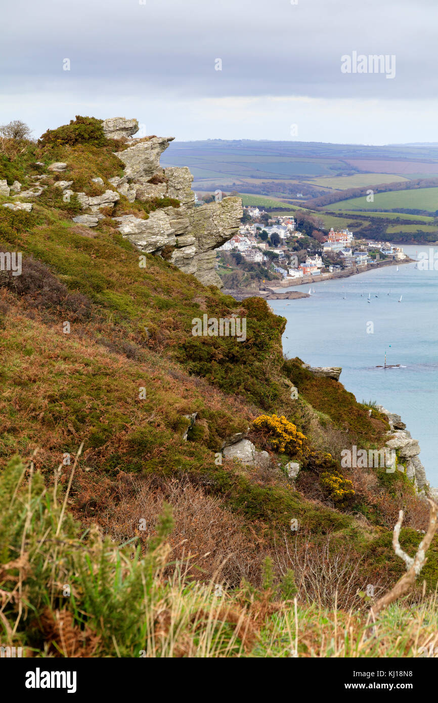 Lower Devonian mica schist rock outcrop in the jagged cliffs of Sharp Tor, frame a view of Salcombe, South devon, UK. Stock Photo