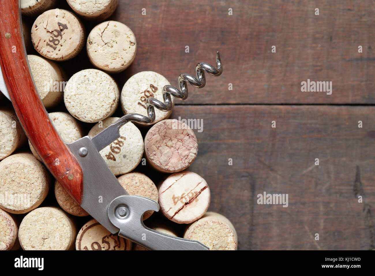 Closeup of corkscrew lying on wine corks on wooden background Stock Photo