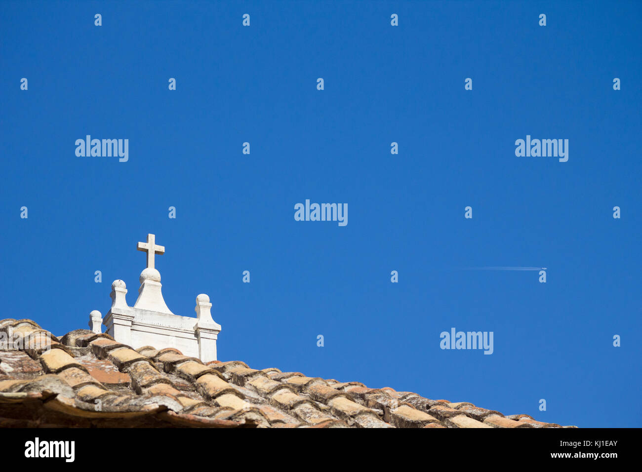 View of a church rooftop with the top of the bell tower and the cross visible Stock Photo