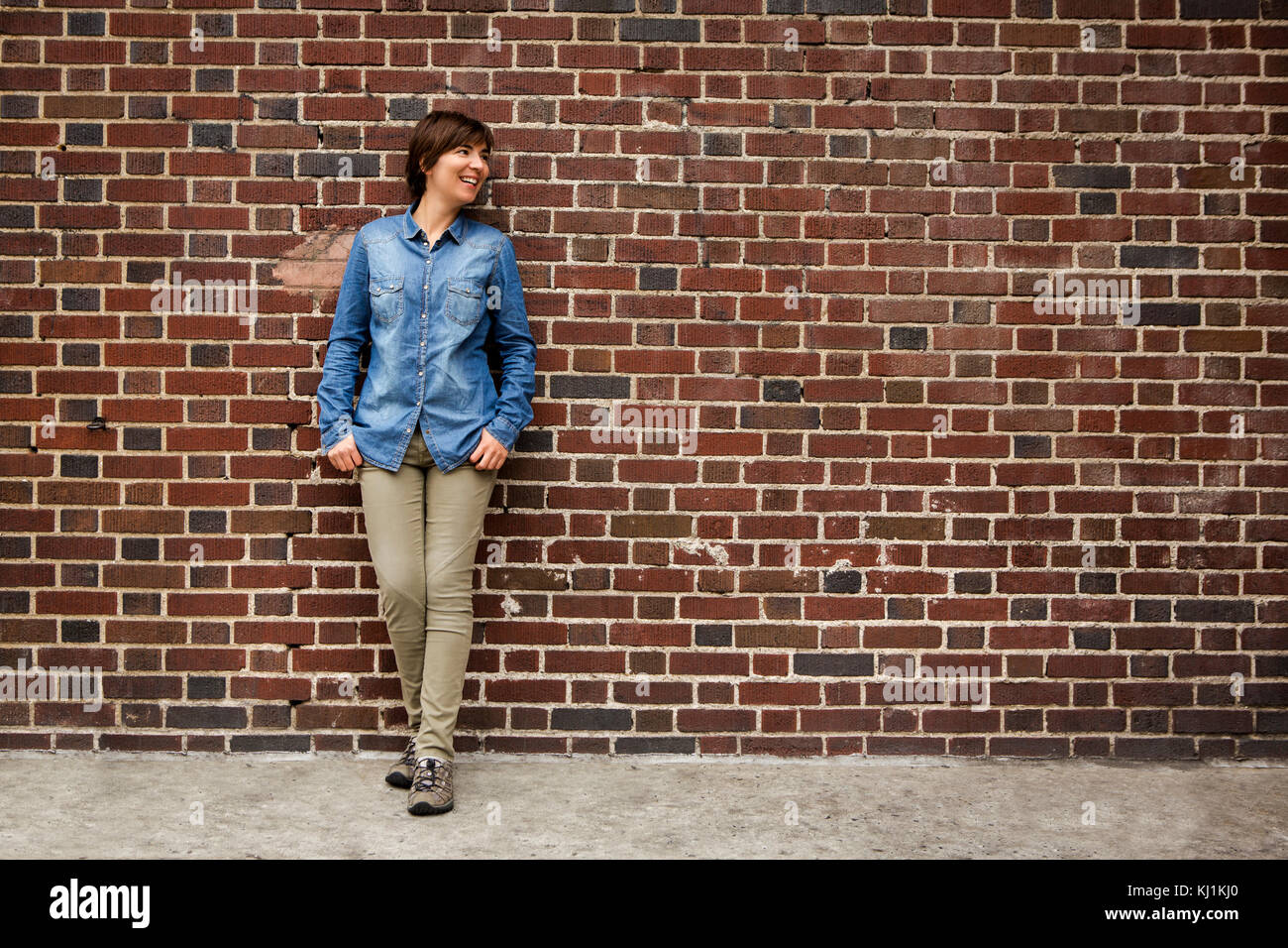 Outdoor portrait of a woman in front of a brick wall Stock Photo - Alamy
