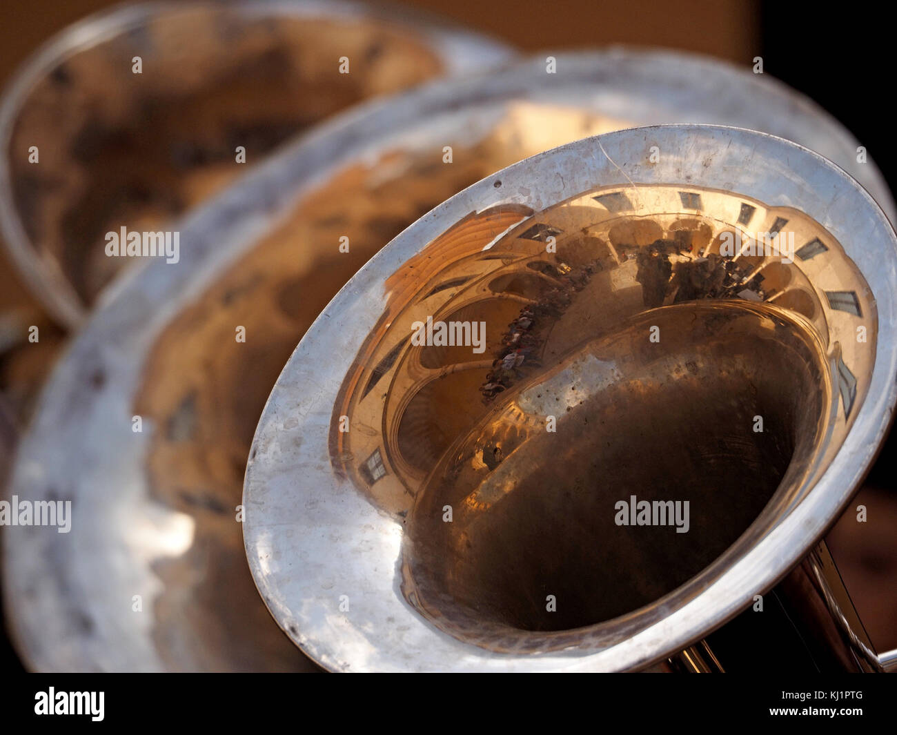 distorted reflections of buildings and sky in three brass instruments ...