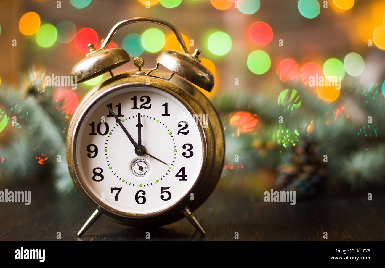 Vintage clock approaching midnight and festive Christmas lights Stock Photo