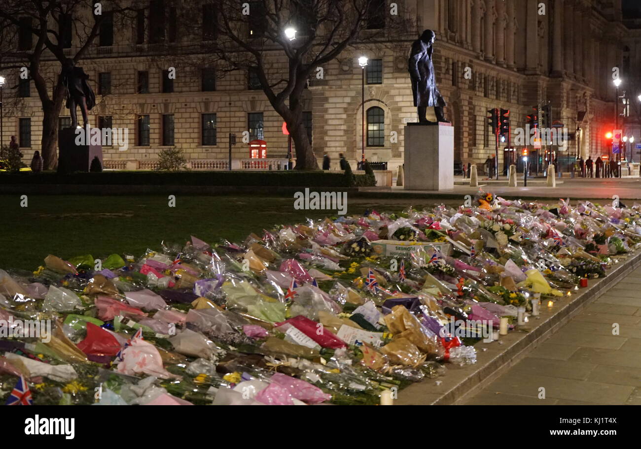 Flowers and tributes decorate Parliament green opposite the British Parliament in London, after the 21 March 2017, terrorist attack, on Westminster Bridge, and Parliament. The attacker drove a vehicle into pedestrians on Westminster Bridge and a crowd of people near Stock Photo
