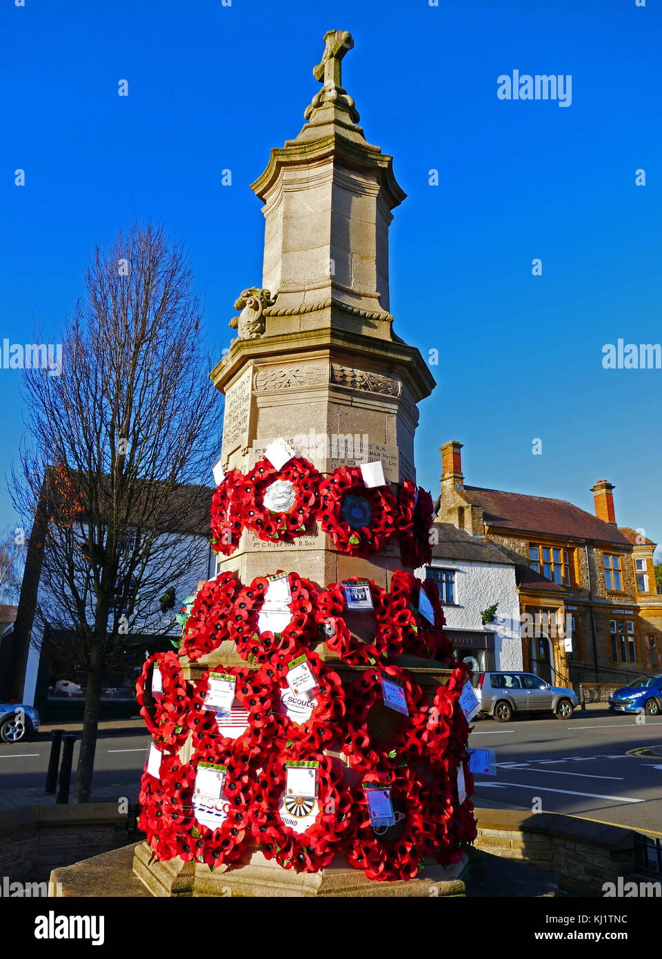 War memorial in the town centre at Brackley, Northamptonshire England; covered with poppy wreaths for Rememberance Day in November. Dated 21st Century Stock Photo