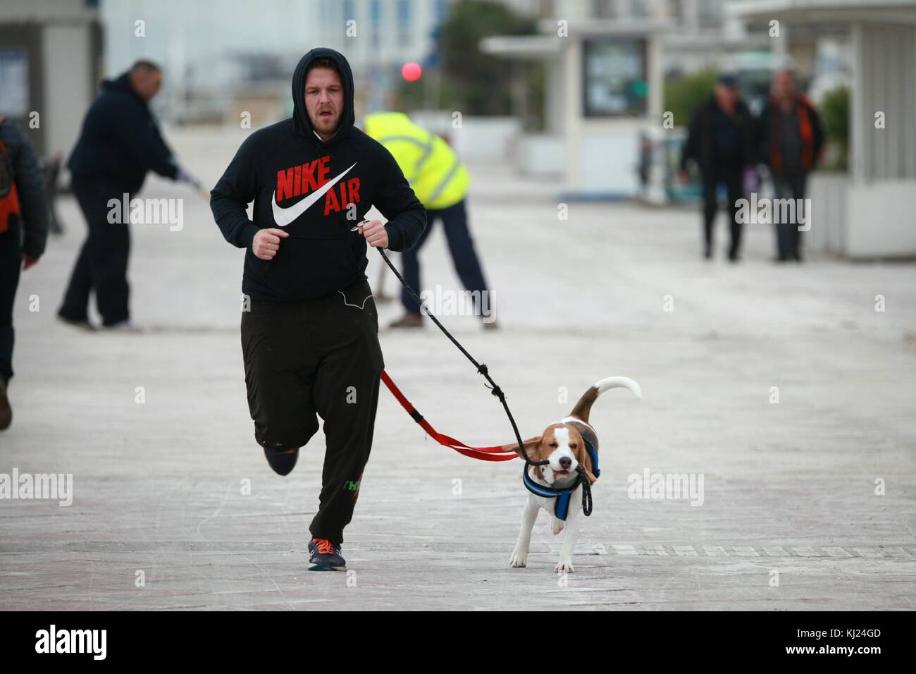 Hastings, East Sussex, UK. 21st November 2017. A man with a hoody jogging along the Hastings promenade seafront with his dog out for exercise. Photo Credit: Paul Lawrenson /Alamy Live News Stock Photo