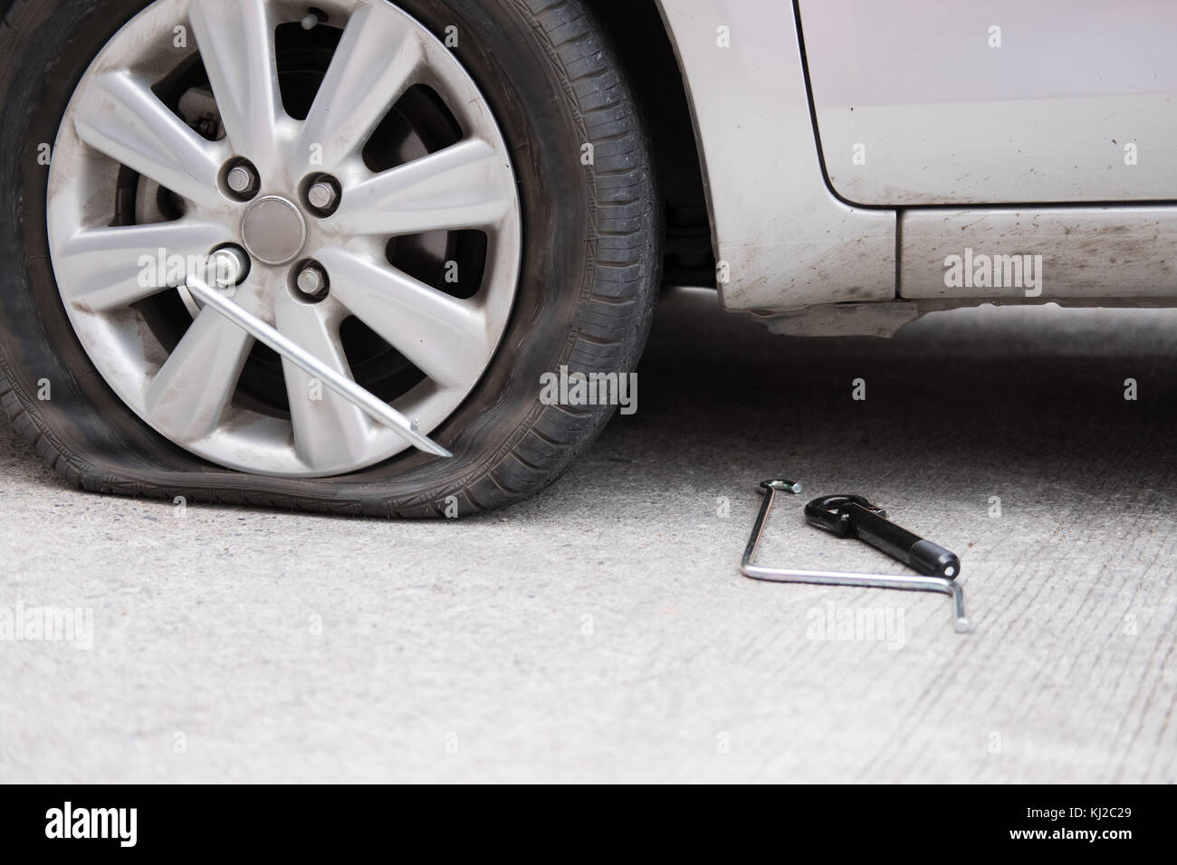 Car tire leak because of nail pounding. flat tyre on road. Flatten