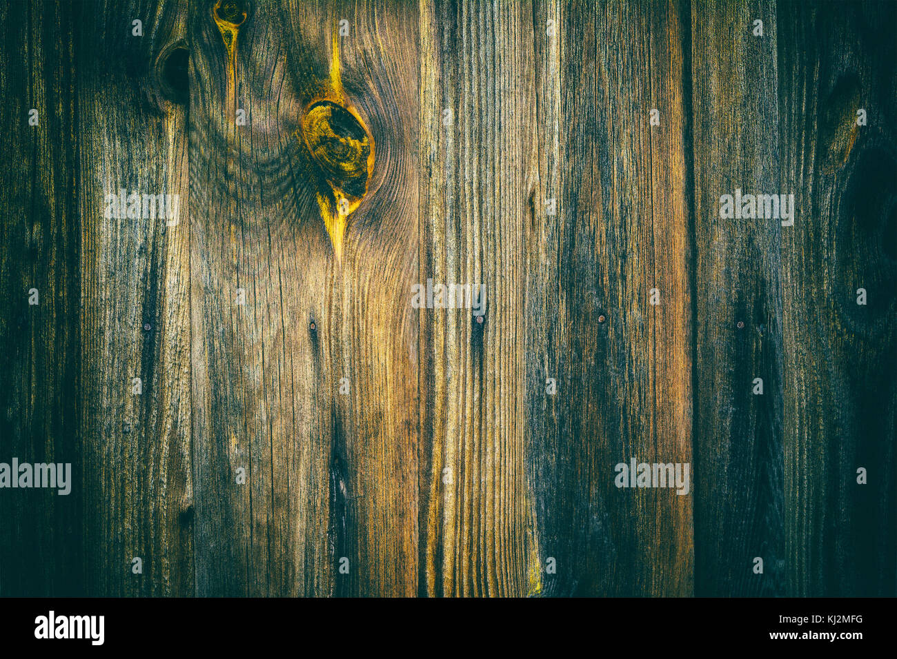 Dark grunge texture with vertical stripes of old boards. Background from wooden faded planks with decorative yellow knot. Stock Photo
