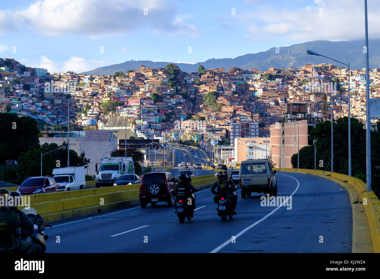 Venezuela, Santiago de Leon de Caracas: Guzm‡n Blanco shanty towns in the upper city and members of the National Guard riding motorbikes on the road Stock Photo