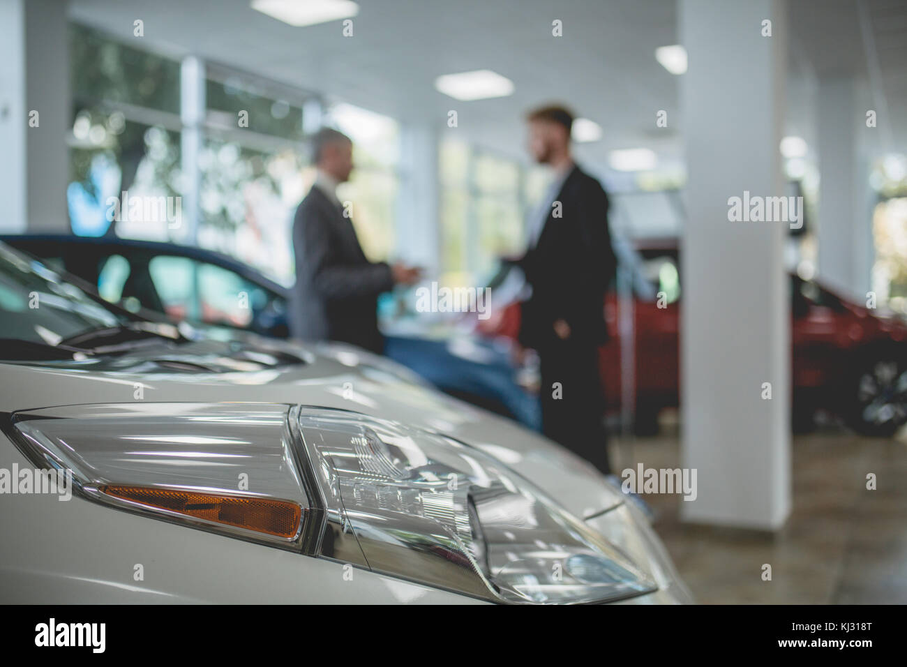 Auto showroom, dealer talking with buyer. Stock Photo