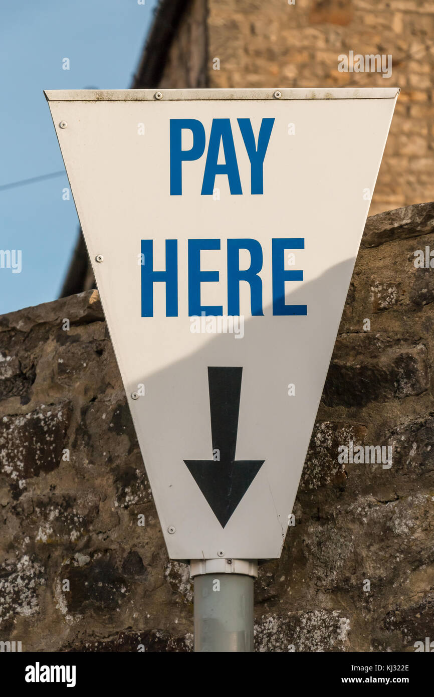 Pay Here sign above a pay and display car park ticket machine with arrow pointing downwards Stock Photo