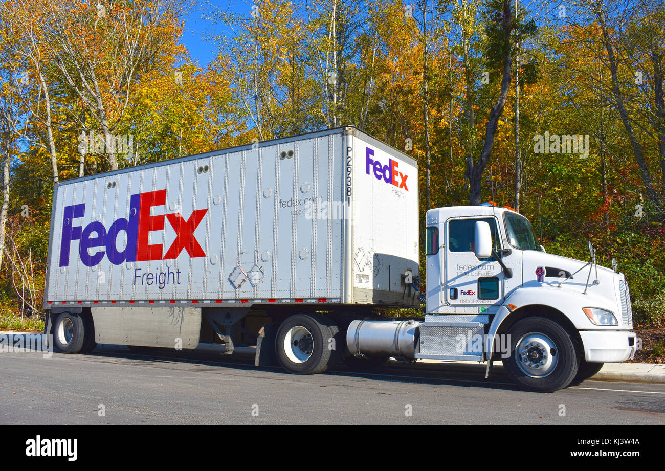 FedEx Semi truck parked along a curb in front of beautiful autumn trees. Stock Photo