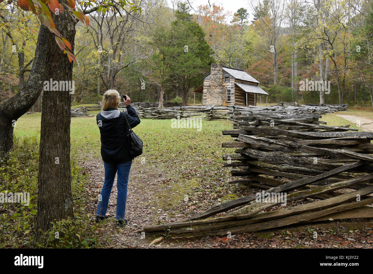 Woman photographing the historic John Oliver Cabin in autumn, Cades Cove, Great Smoky Mountains National Park, Tennessee Stock Photo