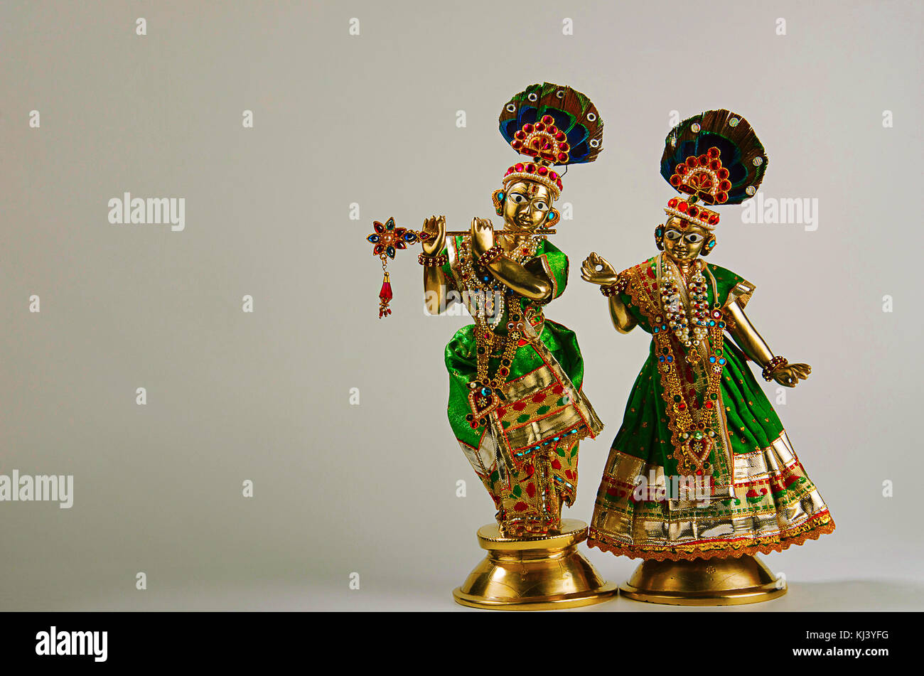 Brass statue of Lord Krishna with flute and Radha (full figure) with mukut or crown on light grey background Stock Photo