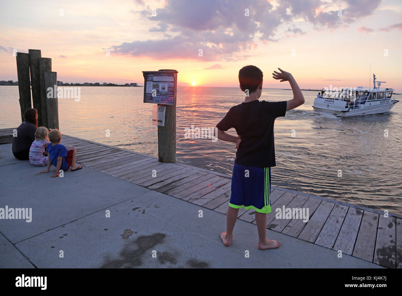 Boy waving to water taxi, Fair Harbor, Fire Island, NY, USA Stock Photo