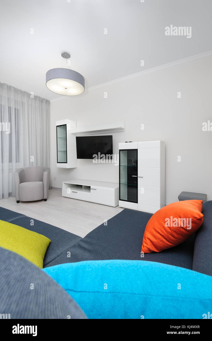 White living room with TV set, chair and grey sofa Stock Photo - Alamy