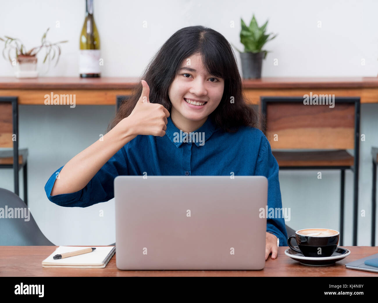 Asia woman freelancer thumbs up and smile using laptop with coffee cup in cafe restaurant,woman working outside office,digital lifestyle concept Stock Photo