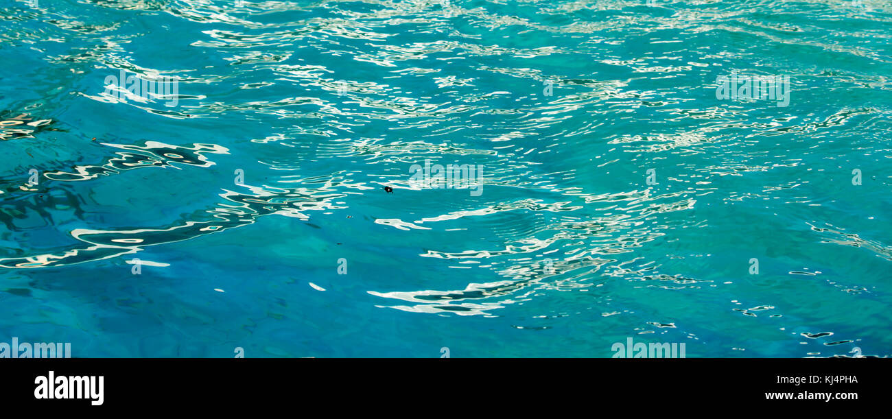 Aquamarine water in an outdoor swimming pool in summer is