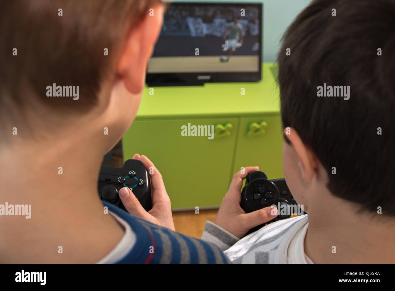 Brothers Play Videogames On Television At Home, Rear View Stock Photo