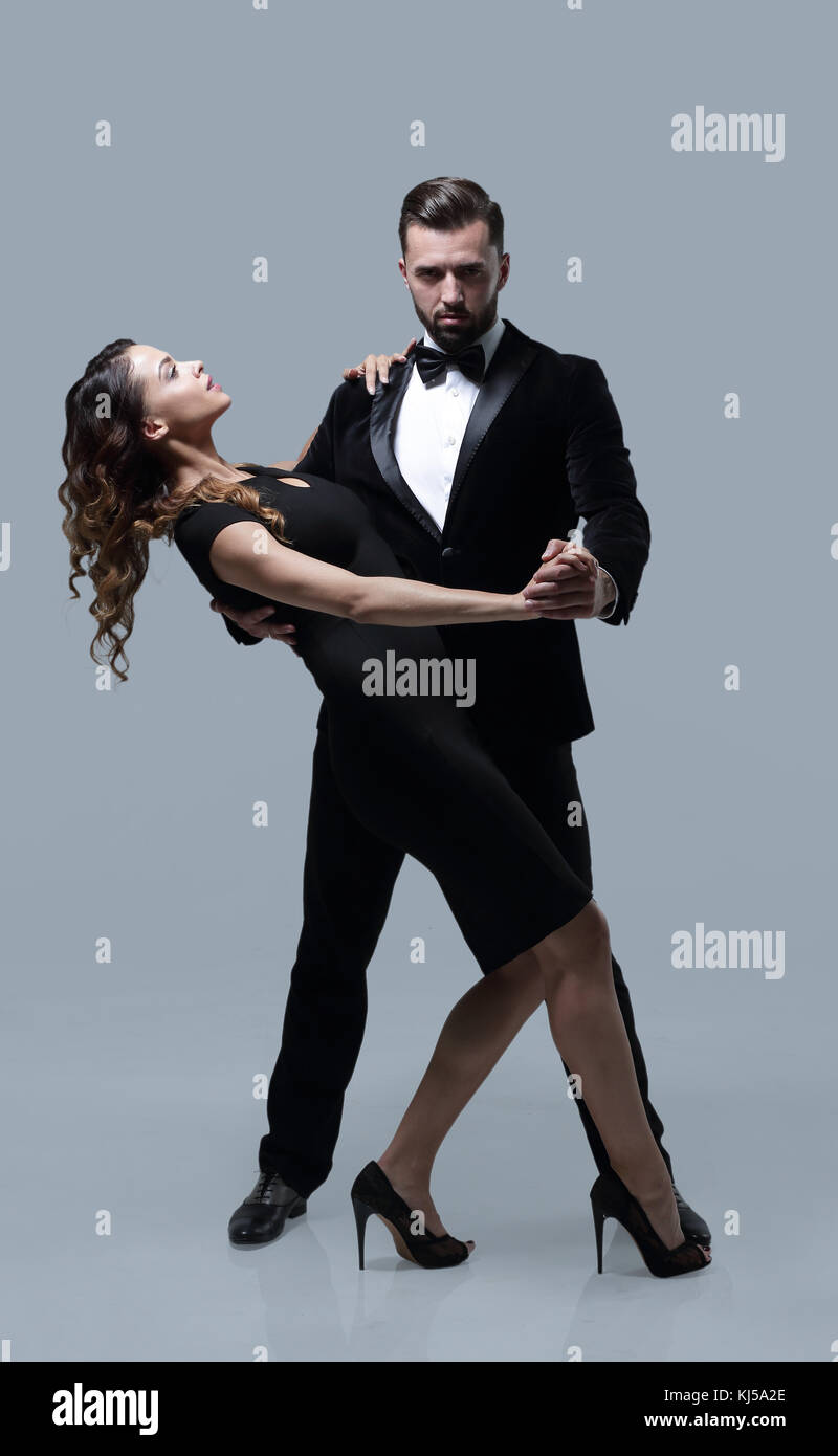 A man and a woman dancing argentinian tango on gray studio background