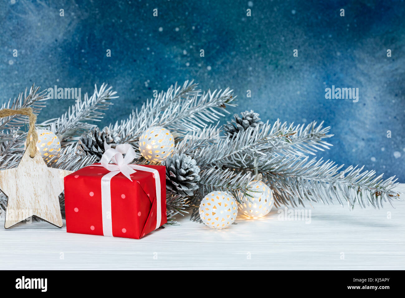 fir tree branch with light garlands, christmas decorations and gift box on blue background Stock Photo