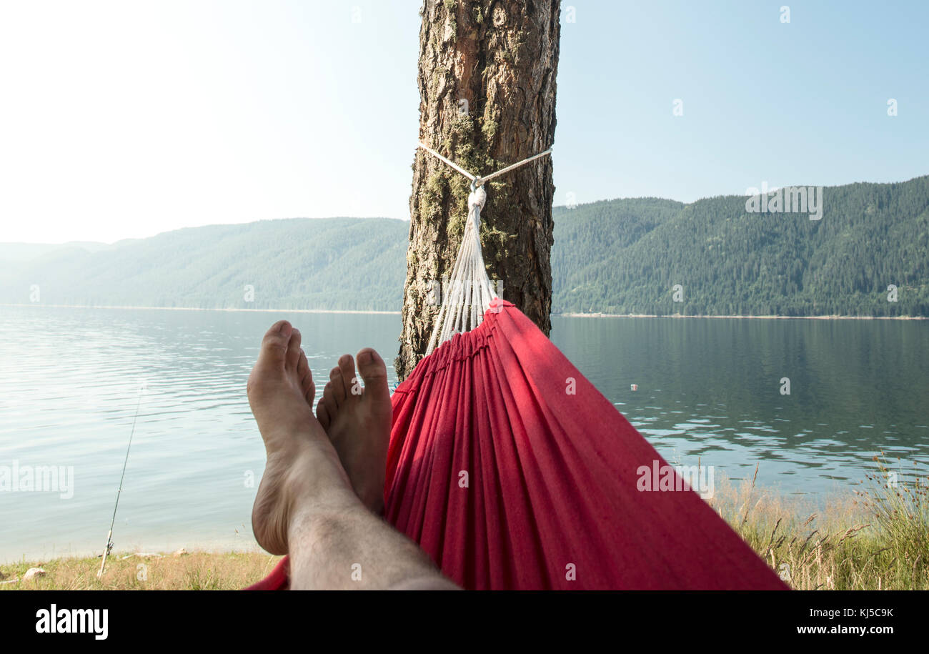 Man in hammock on mountain lake shore Stock Photo Alamy