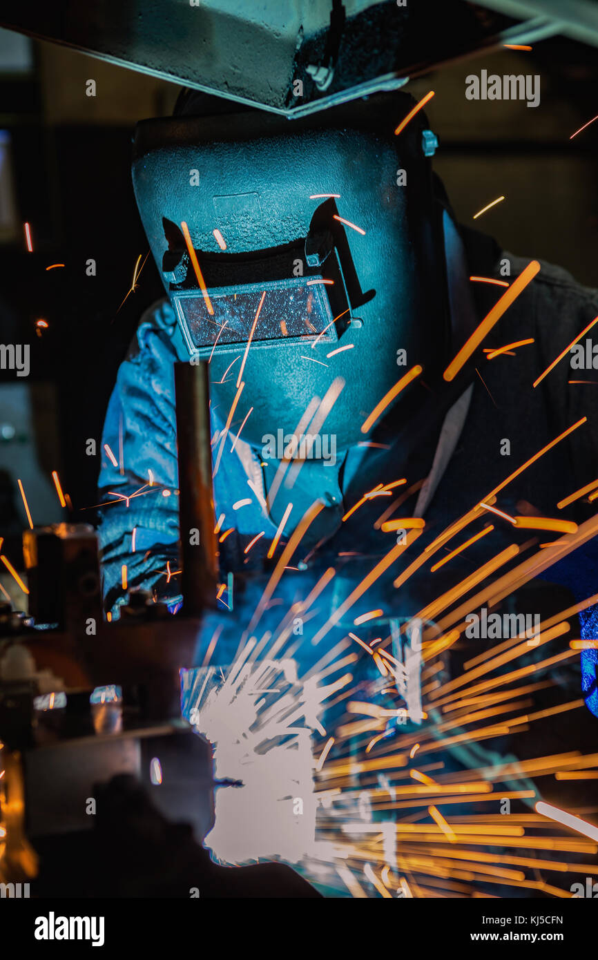 Worker is welding automotive part in car factory Stock Photo