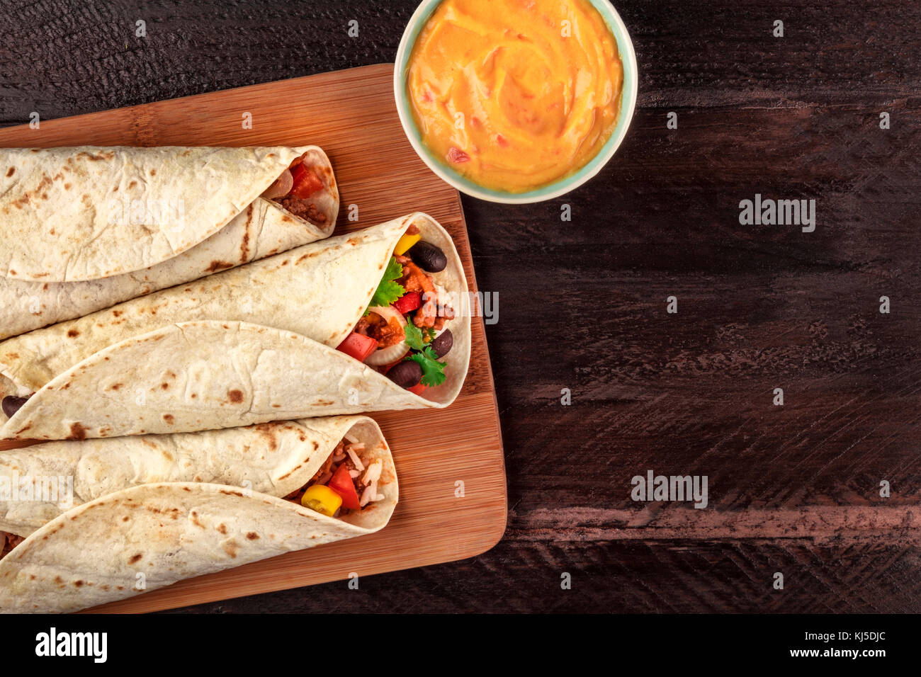 Mexican burritos with cheese salsa and copyspace, overhead shot Stock