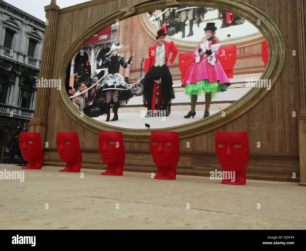 Big screen with Judges podiums in the form of red masks at the Venice Carnival (Carnevale di Venezia), an annual festival held in Venice, Italy. Started to recall a victory of the 'Serenissima Repubblica' against the Patriarch of Aquileia, in the year 1162. In the honour of this victory, the people started to dance and gather in San Marco Square. Stock Photo