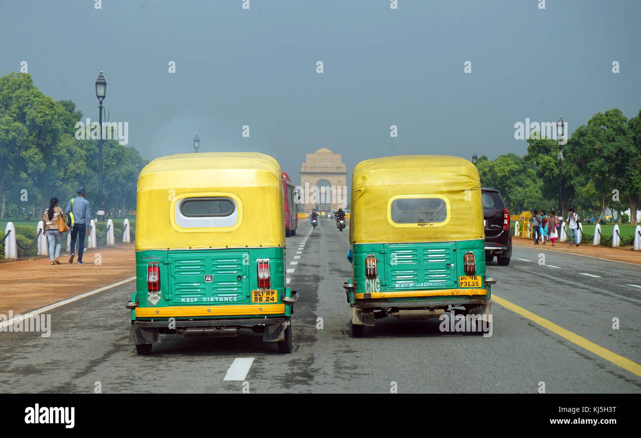 Small yellow and green taxis drive towards the India Gete in Delhi, India Stock Photo